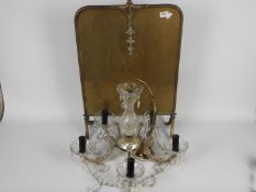 A five branch glass chandelier and a brass firescreen.