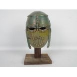 Studio pottery model of an Anglo Saxon helmet on wooden stand,