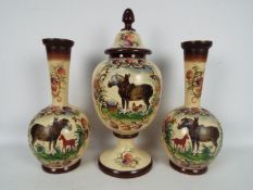 A garniture of three hand painted glass vases comprising ovoid pedestal vase with cover,