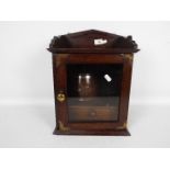 An oak smokers cabinet with single glazed door, brass mounts, tobacco jar,