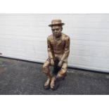 A large cast brass sculpture of a seated gentleman wearing a suit,