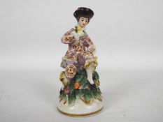 An early 20th century porcelain figure of a seated gentleman, gold anchor mark to the base,
