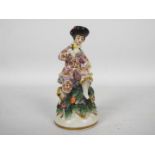 An early 20th century porcelain figure of a seated gentleman, gold anchor mark to the base,