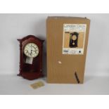 A modern Westminster chime wall clock with key and pendulum, boxed.