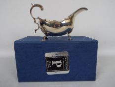 A silver sauce boat raised on tripod supports and with scroll handle, Birmingham assay,