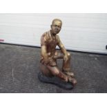 A large cast brass sculpture of a seated gentleman wearing a suit,