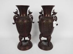 A pair of cast metal vases with twin chilong handles, cast decorative panels,