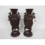 A pair of cast metal vases with twin chilong handles, cast decorative panels,