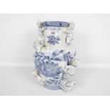A large blue and white vase with floral decoration and applied figures of climbing boys,