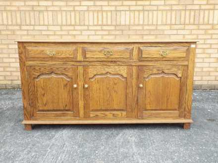 A sideboard with three short drawers over three enclosed cupboards,