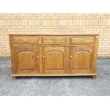 A sideboard with three short drawers over three enclosed cupboards,