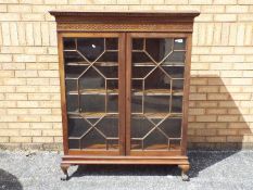 A twin door, astragal glazed display cabinet with carved decoration,