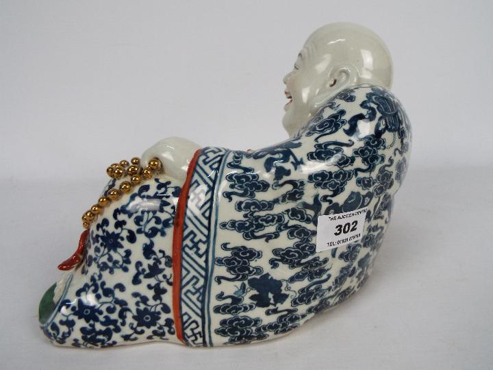 A Chinese ceramic model depicting Budai in reclining pose clutching a string of gilt beads, - Image 4 of 7