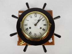 A Schatz brass bulkhead clock with ship's wheel surround.