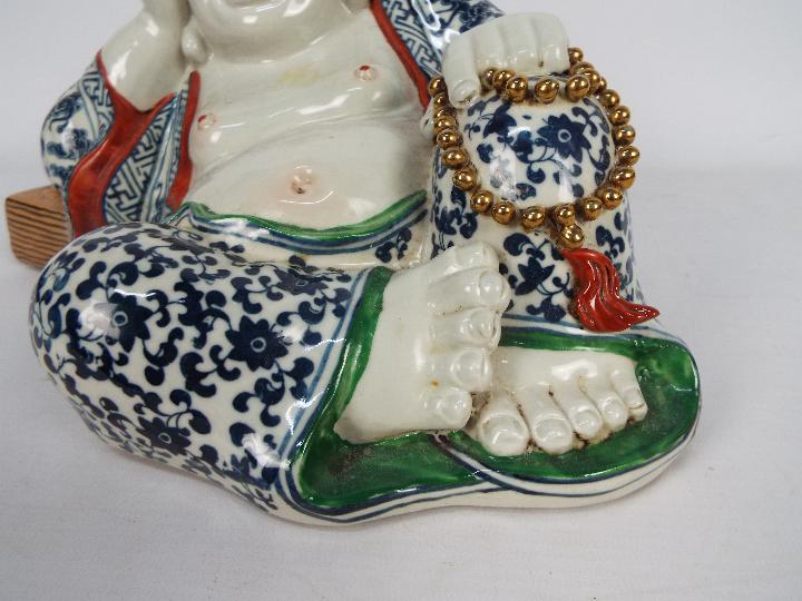 A Chinese ceramic model depicting Budai in reclining pose clutching a string of gilt beads, - Image 2 of 7