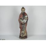 A reconstituted stone garden ornament depicting a Chinese gentleman in flowing robes holding a fish,