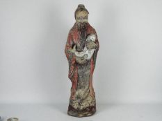 A reconstituted stone garden ornament depicting a Chinese gentleman in flowing robes holding a fish,