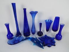 A collection of items of blue glass to include vases, dolphin model, bowls and similar.