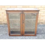 A wall mounted oak display cabinet, the twin glazed doors opening to reveal three internal shelves,
