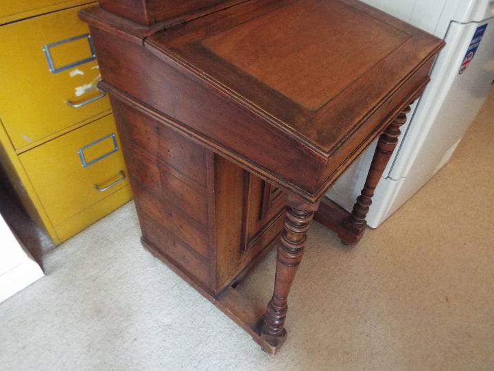 A Victorian davenport with cupboard to the side enclosing four drawers, brass castors,