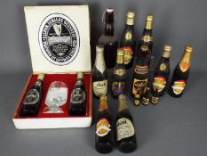 A collection of vintage beer bottles with contents to include Guinness, Harp, Skol,