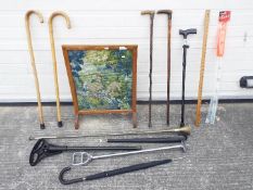 A collection of walking sticks, two with silver collars, shooting sticks and other.
