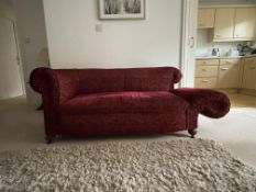 An antique drop-arm sofa with scroll back and arms, raised on four castored supports,