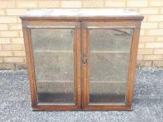 A wall mounted oak display cabinet, the twin glazed doors opening to reveal three internal shelves,