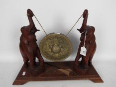 A vintage carved wood and brass dinner gong and striker,