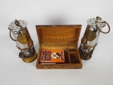 Two safety lamps, both Protector Lamp & Lighting Co Type 6 and a carved wooden box.