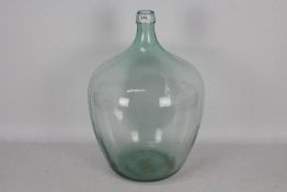 A large, green tinted glass carboy,