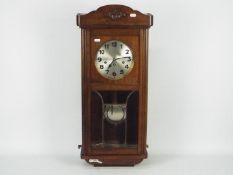 A vintage oak cased wall clock with key and pendulum.