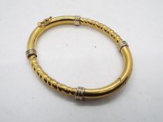 A yellow metal hinged bangle, stamped 9kt, 6 cm across at the widest point, approximately 15.