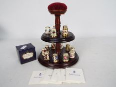 A thimble stand with fifteen Royal Crown Derby thimbles from the Historical Thimble Collection
