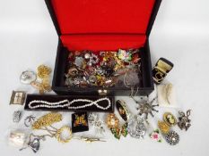 A jewellery box containing costume jewellery to include brooches, rings, necklaces,