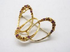 An 18ct yellow gold and ruby set brooch formed as three interlocking ovals each set with three