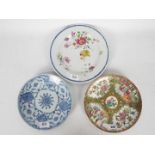 Three plates comprising a Cantonese famille rose example decorated with panels of flowers and