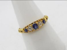 A lady's hallmarked 18 carat yellow gold ring set with three old cut sapphires and two old cut