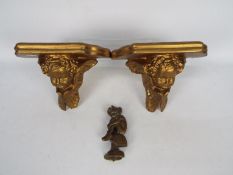 A pair of gilt plaster wall sconces decorated with putto and a vintage brass door knocker in the