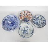Four plates comprising three blue and white and one decorated in the imari palette,