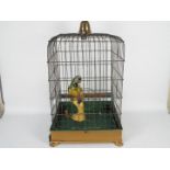 An antique birdcage with removable tray and faux parrot,