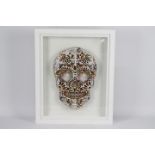 A framed limited edition work depicting a skull decorated with images of £10 notes,