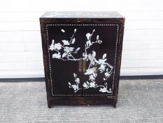 A twin door, black lacquer cabinet decorated with perching birds,