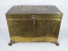 A brass bound, hinge lid chest, raised on four paw feet, approximately 43 cm x 69 cm x 42 cm.