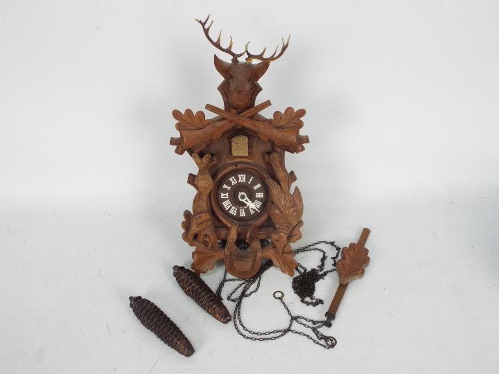A vintage cuckoo clock with pendulum and twin weights.