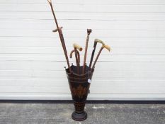 An umbrella / stick stand with a quantity of walking sticks including one with silver collar and