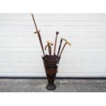 An umbrella / stick stand with a quantity of walking sticks including one with silver collar and