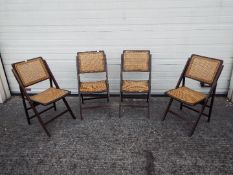 Four folding chairs with cane seats and backrests.