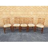 Five ladder back chairs with rush seats.