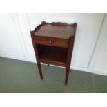 A small cabinet with single drawer over open storage section, raised on fluted tapered supports,